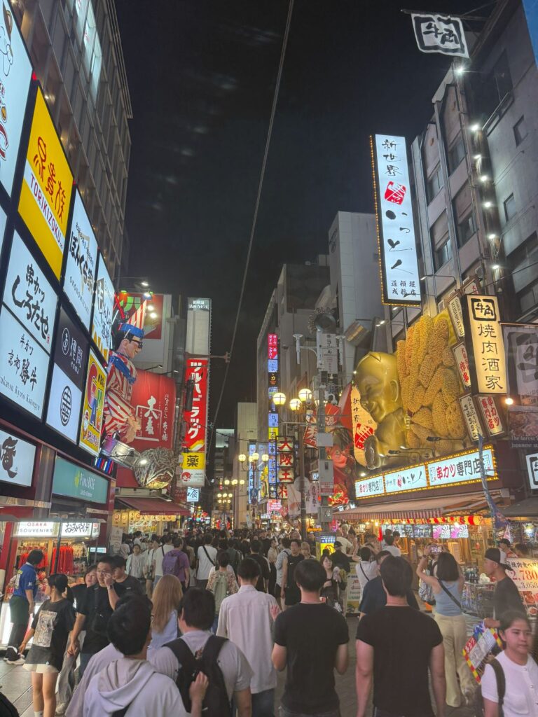 La folla e le insegne luminose di Dōtonbori a Osaka dopo il tramonto