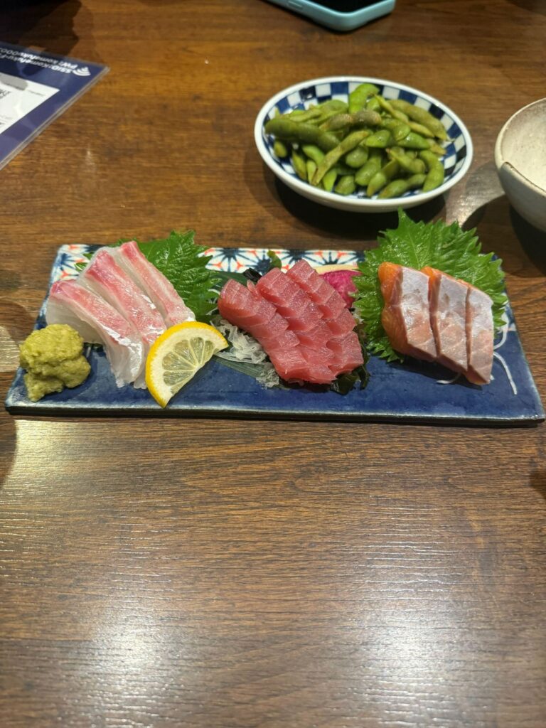 Un vassoio di sashimi misto con wasabi, limone ed edamame