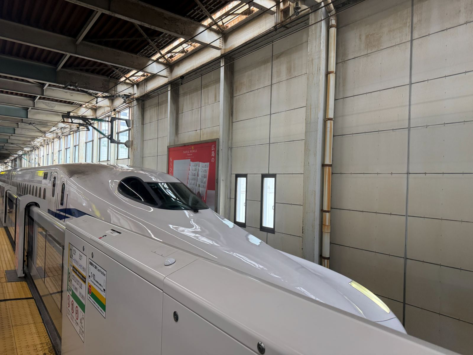 Il muso allungato di uno shinkansen fermo al binario in una stazione giapponese