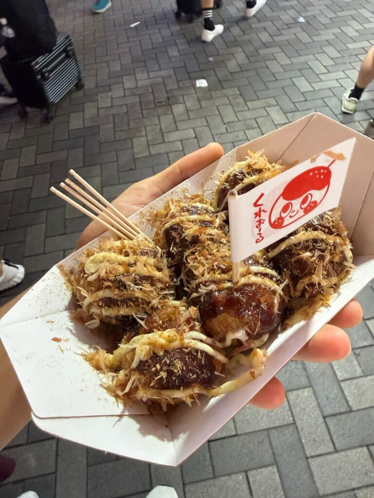 Una vaschetta di takoyaki con katsuobushi tenuta in mano a Osaka