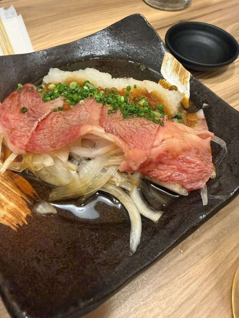Fette di wagyu scottate servite su cipolle con salsa