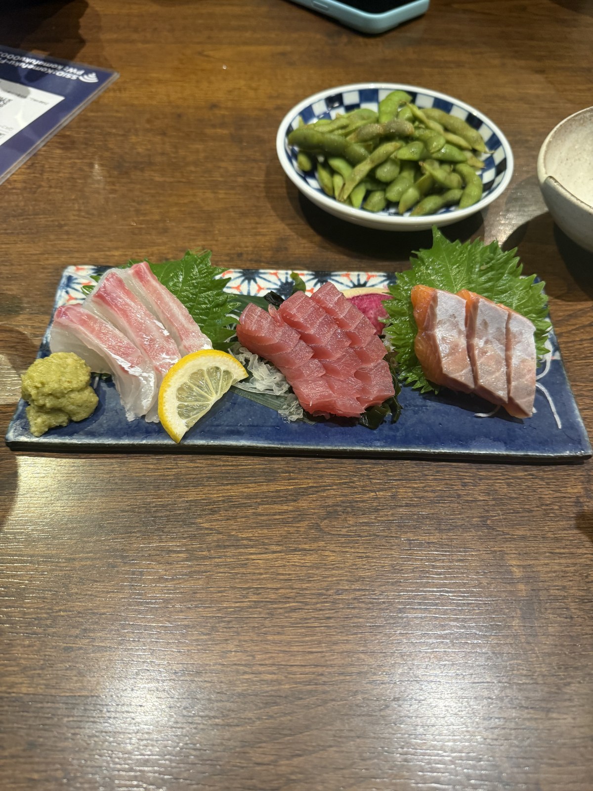 Tris di sashimi con edamame su un tavolo di izakaya in Giappone